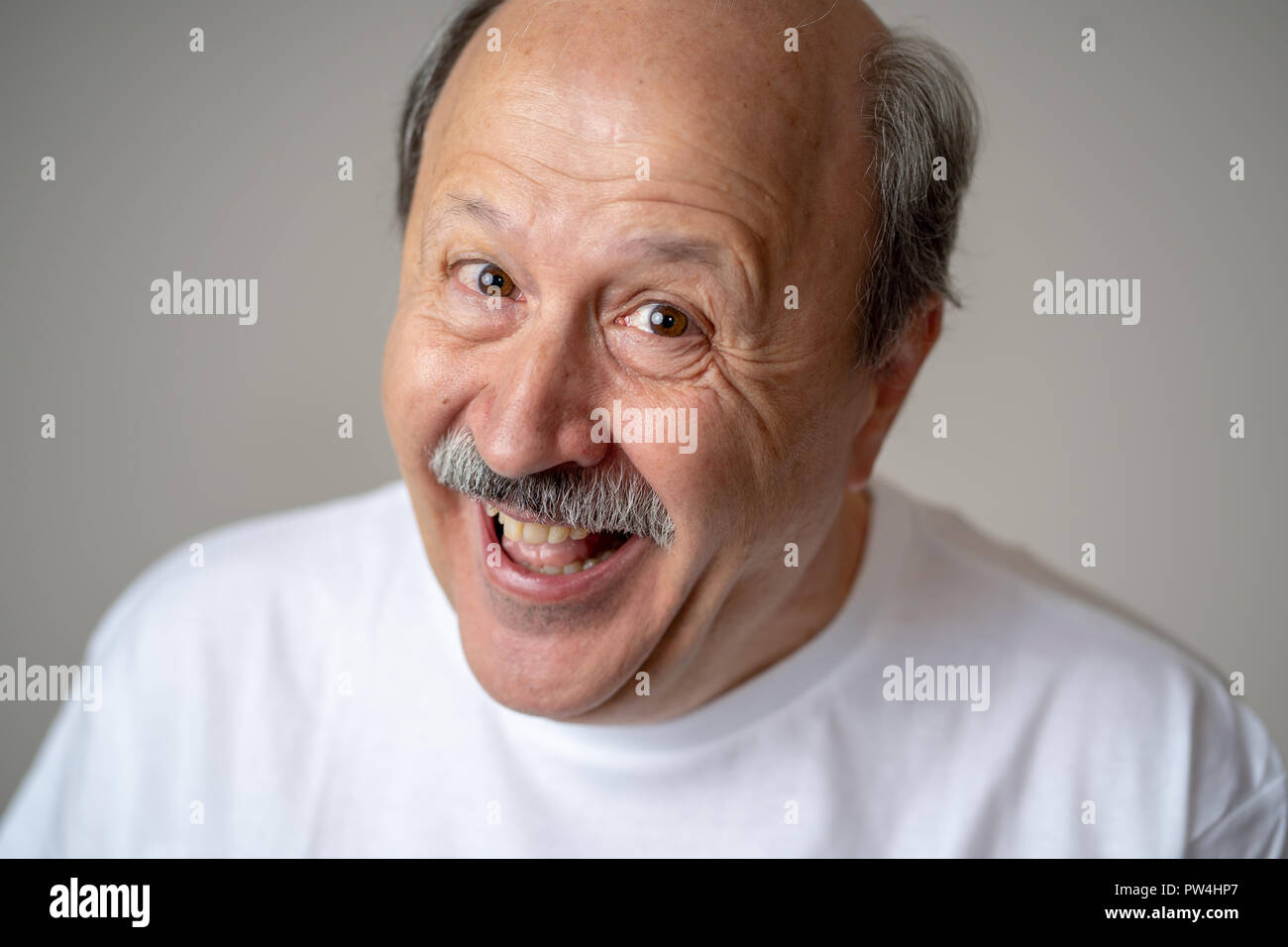 Lächeln und Lachen 60er Jahre alten älterer Mann candid Nahaufnahme portrait in menschliche Gefühle und Mimik Konzept in neutralen Hintergrund isoliert. Stockfoto