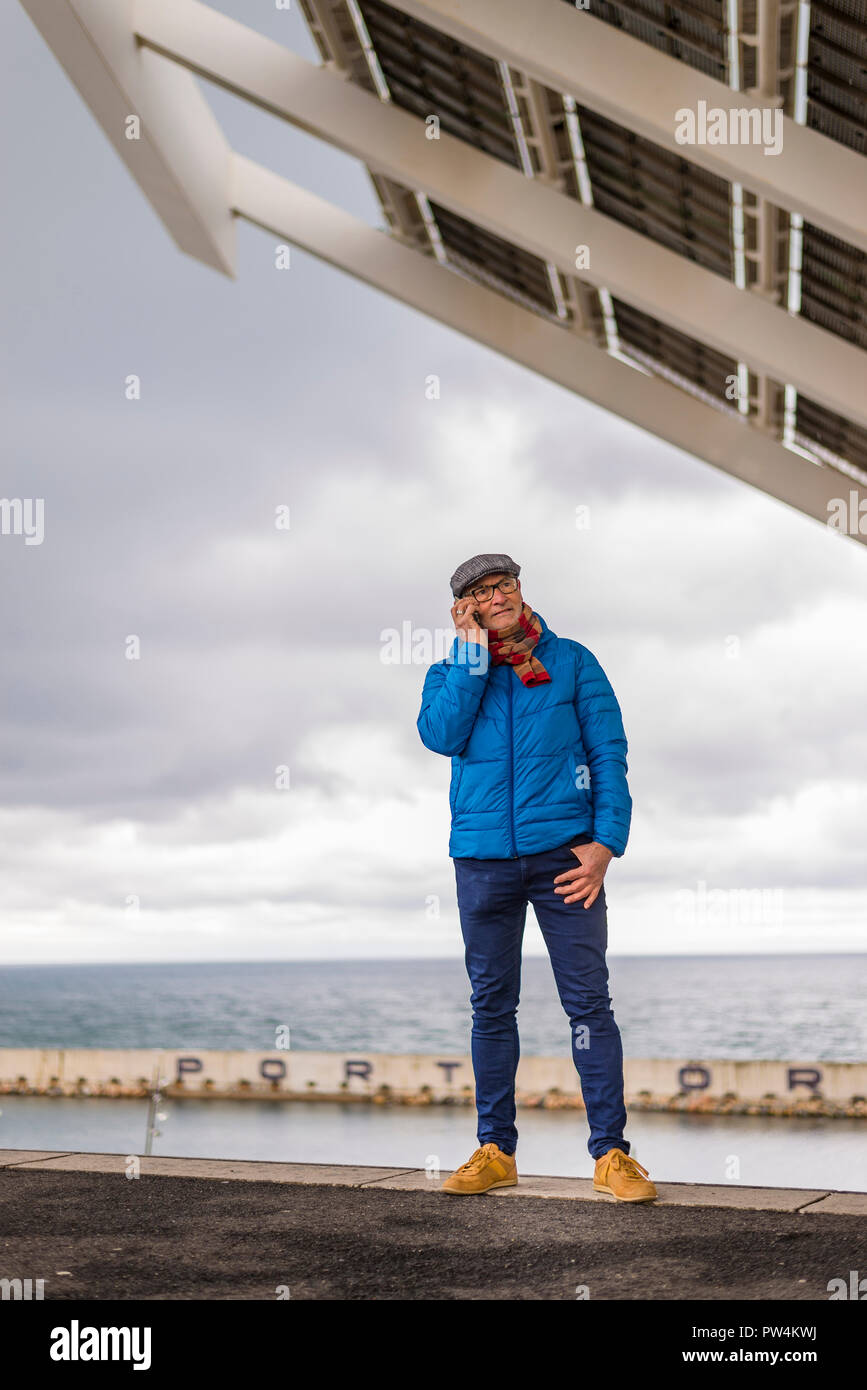 Ältere Menschen im Gespräch durch Smart Phone beim Stehen auf See gegen bewölkter Himmel Stockfoto