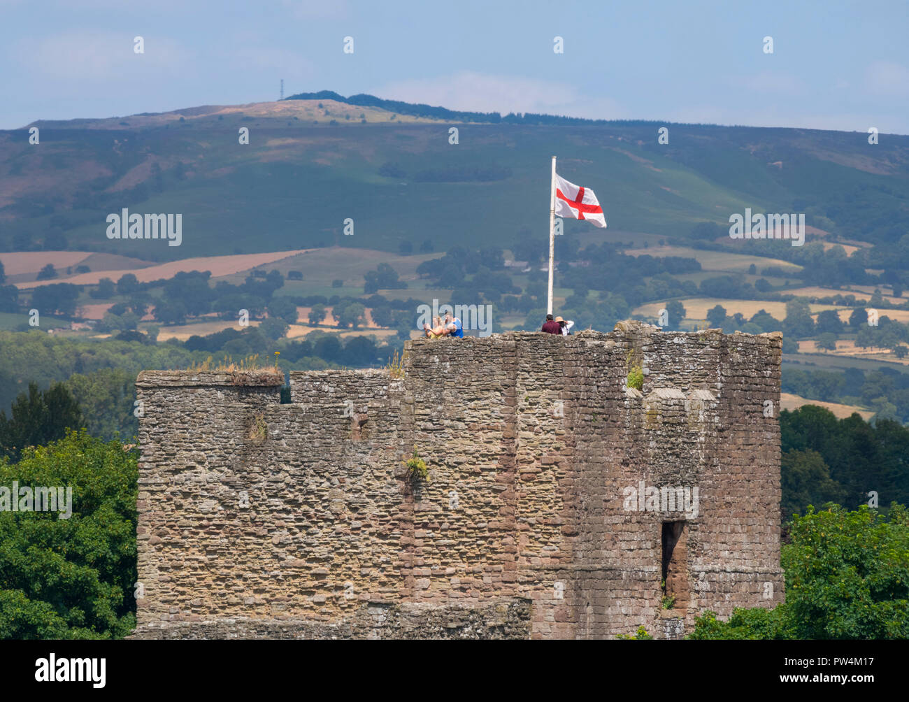 St George's Flagge vom Großen Turm von Ludlow Castle, Shropshire, mit braunen Clee im Hintergrund zu sehen. Stockfoto