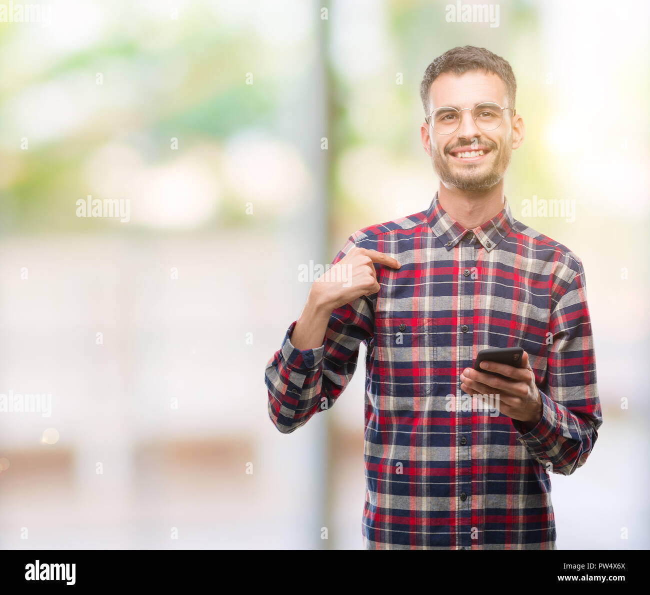 Junge hipster erwachsenen Mann hält mit Überraschung Gesicht zeigenden Finger zu sich Smartphone Stockfoto