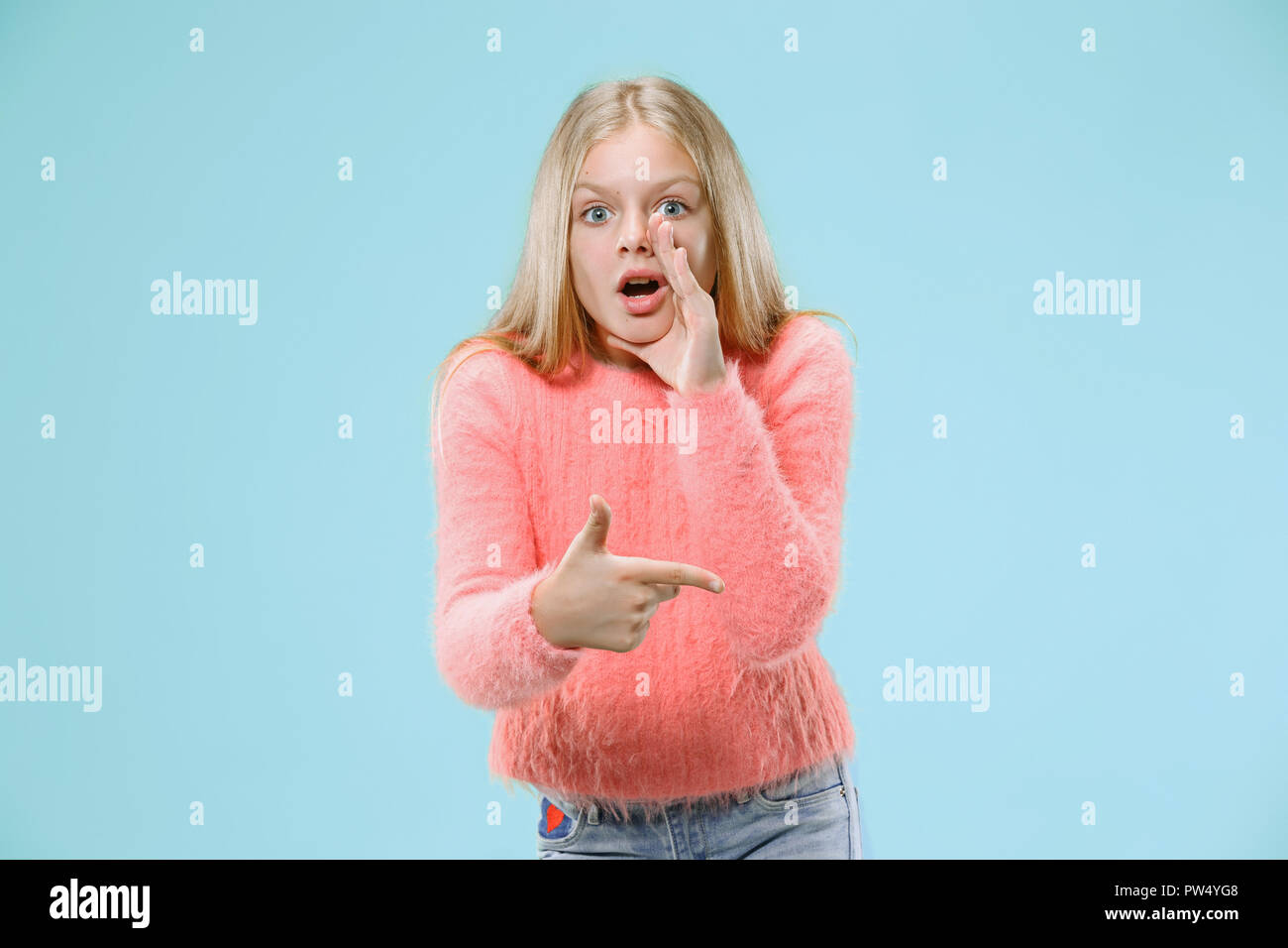 Geheimnis, Klatsch-Konzept. Junge Teen Girl whispering ein Geheimnis hinter ihrer Hand am trendigen Blau studio Hintergrund isoliert. Junge emotionale Mädchen. Menschliche Gefühle, Mimik Konzept. Stockfoto