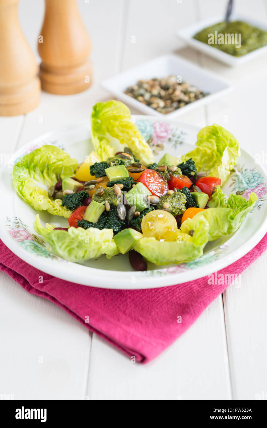 Dreifarbige Salat mit Bohnen, Tomaten, Kohl und Avocado auf einem Bett von Juwel Kopfsalat. Stockfoto