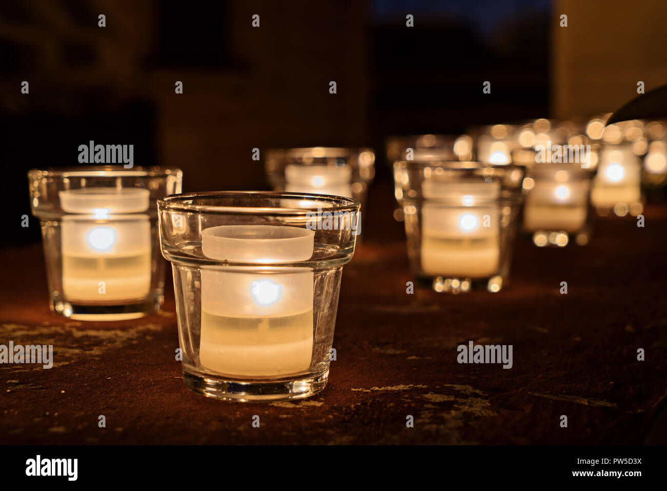 Große Gruppe von Gläsern mit brennenden Kerzen auf dem dunklen Hintergrund, selektive konzentrieren. Hygge Konzept Stockfoto