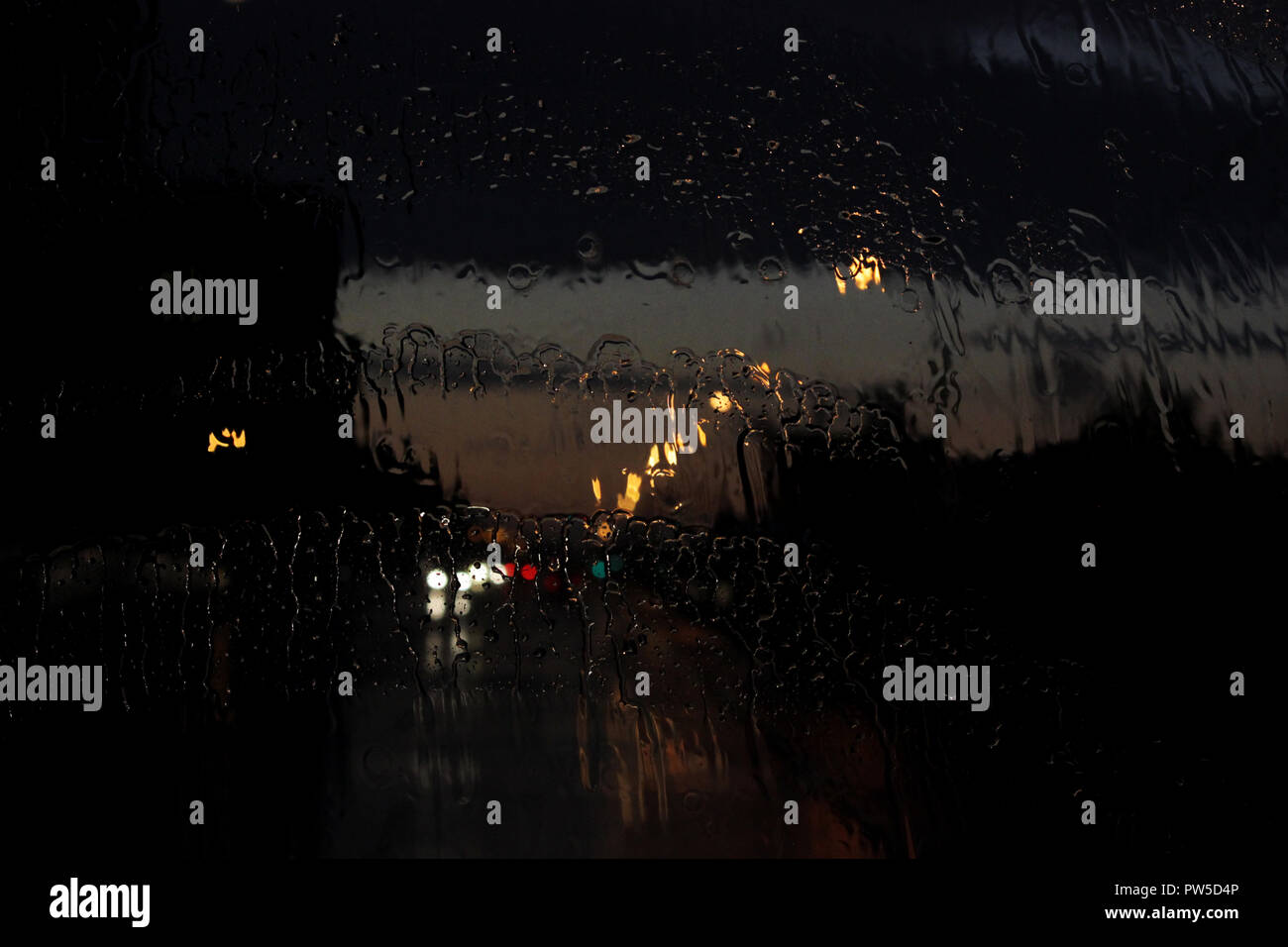 Homecoming. Bokeh Lichter, nassen verschwommene Sicht des Straßenverkehrs in Gatschina an einem regnerischen Abend durch den Bus Fenster vorne. Regentropfen und Spuren aus der Stockfoto