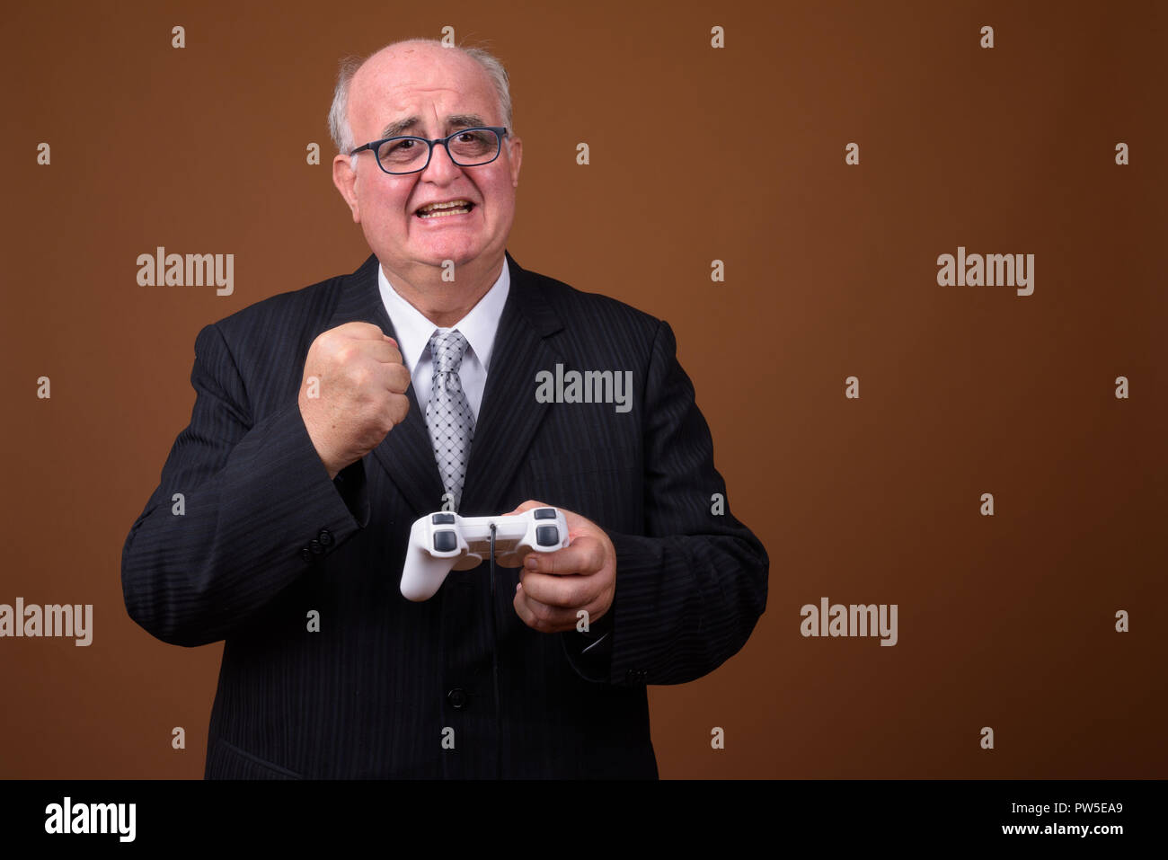 Übergewicht älterer Geschäftsmann spielen und der Holding Game Controller Stockfoto