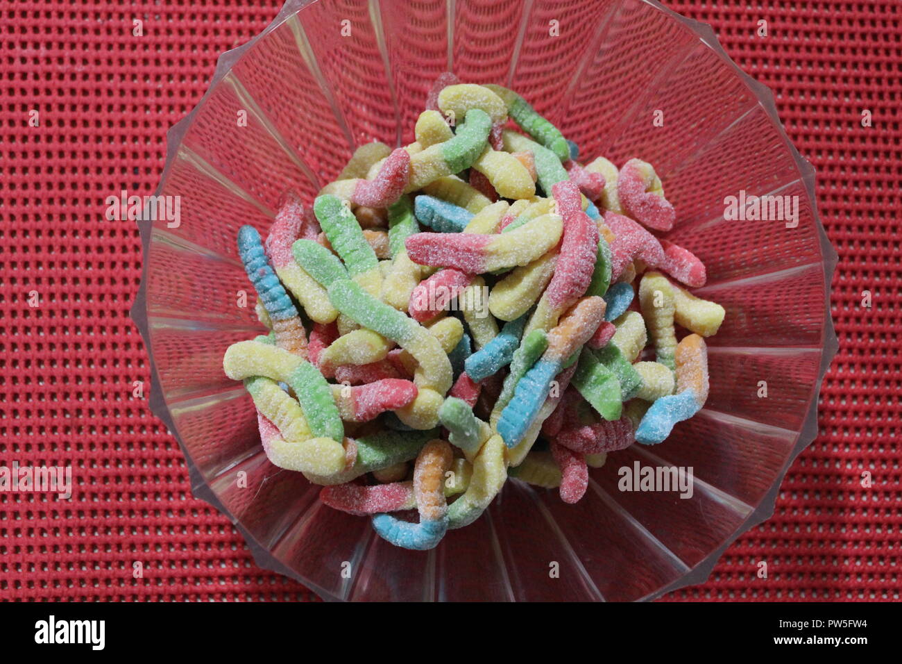 In der Nähe von Gummibärchen Wurm candy in Plastik Schüssel auf eine orange Tabelle Stockfoto