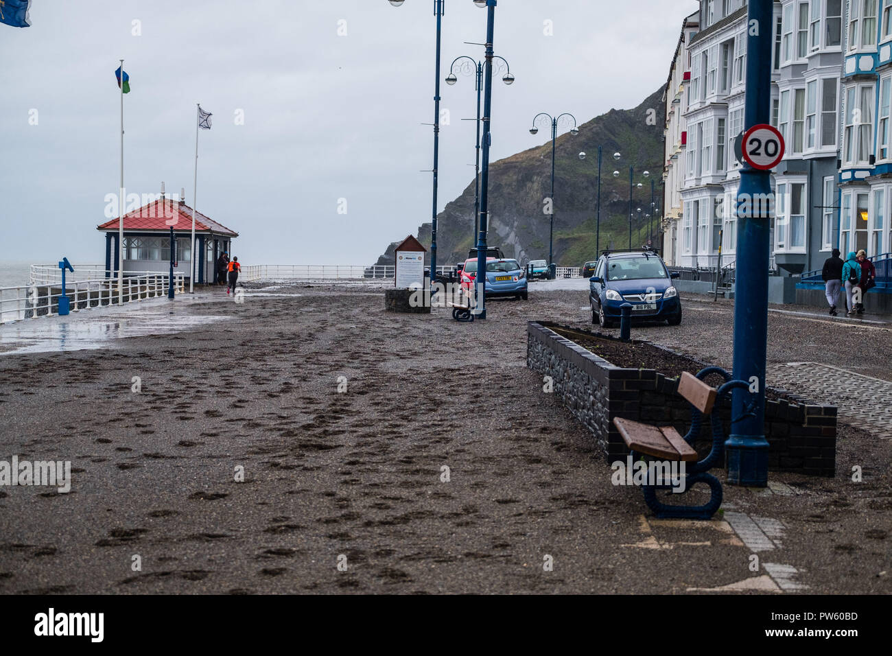 Aberystwyth, Wales, UK. 13. Oktober, 2018. UK Wetter: Nach einer Nacht, der starken Winde und Gezeiten im Zusammenhang mit dem Sturm Callum, der Promenade in Aberystwyth ist in Hunderte von Tonnen von Sand und Kies bedeckt. Mit einer weiteren Flut an diesem Morgen, und die Winde wieder über 50 mph wehenden, weitere Schäden zu rechnen ist. Foto: Keith Morris/Alamy leben Nachrichten Stockfoto