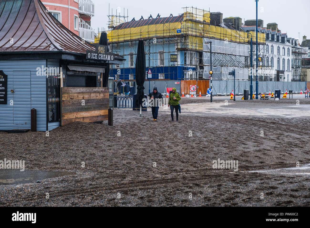 Aberystwyth, Wales, UK. 13. Oktober, 2018. UK Wetter: Nach einer Nacht, der starken Winde und Gezeiten im Zusammenhang mit dem Sturm Callum, der Promenade in Aberystwyth ist in Hunderte von Tonnen von Sand und Kies bedeckt. Mit einer weiteren Flut an diesem Morgen, und die Winde wieder über 50 mph wehenden, weitere Schäden zu rechnen ist. Foto: Keith Morris/Alamy leben Nachrichten Stockfoto