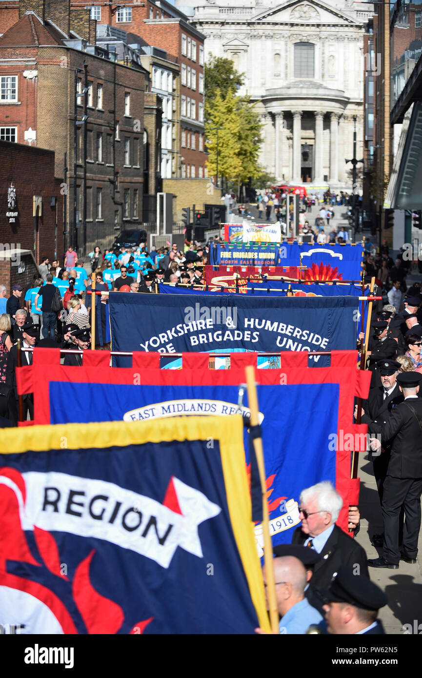 London, Großbritannien. 13. Oktober 2018. Nach einem förmlichen Kranzniederlegung am Nationalen Feuerwehrmänner' Memorial neben der St. Paul's Cathedral, in Erinnerung an gefallene Feuerwehrmänner aus allen Feuerwehr in Großbritannien, Mitglieder der Feuerwehren Union (FBU) Teil in einer formellen Prozession über die Millennium Bridge nehmen, gefolgt von einem Service in Southwark Kathedrale den 100. Jahrestag der Gründung der FBU zu gedenken. Die Aktivitäten sind die bisher größte Festveranstaltung für Feuerwehrmänner, die in der Linie der Aufgabe getötet. Credit: Stephen Chung/Alamy leben Nachrichten Stockfoto