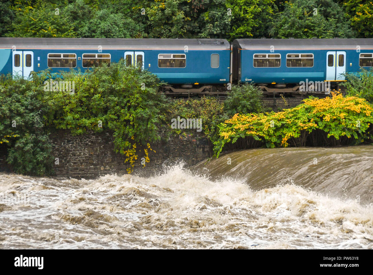 RADYR, in der Nähe von Cardiff, Wales - 13. OKTOBER 2018: Am letzten Tag den Betrieb seiner 15-jährigen Wales und die Grenzen rail Franchise, Arriva Trains Wales Pendlerzug übergibt die schweren Hochwasser am Fluss Taff am Radyr Wehr in der Nähe von Cardiff. Die extrem hohen Wasserstand ist das Ergebnis der Sturm Callum. Der Fluss Taff, die in die Bristol Kanal an der Cardiff Bay läuft, läuft Wasser aus der Brecon Beacons Berge und die South Wales Täler. Credit: Ceri Breeze/Alamy leben Nachrichten Stockfoto