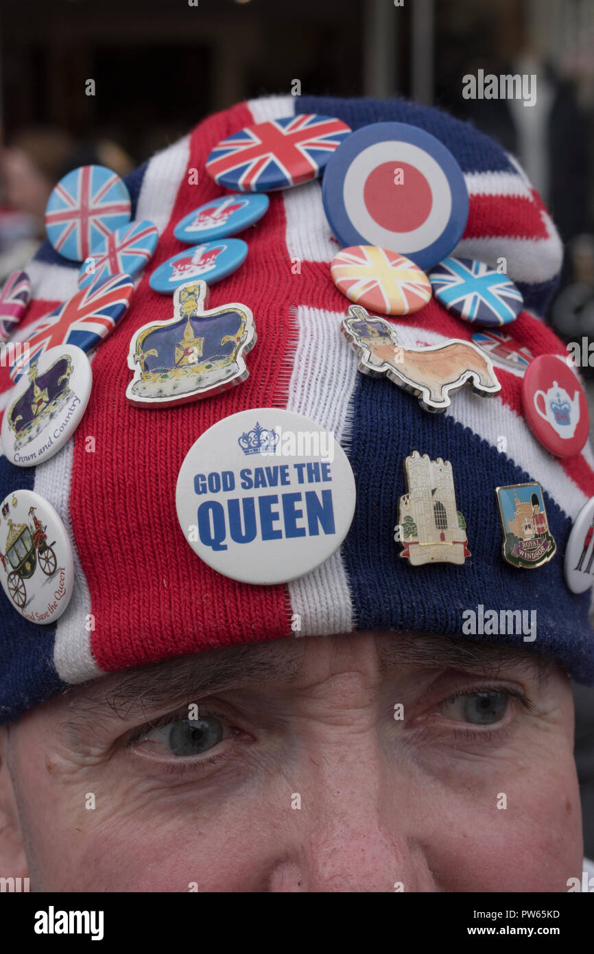 Die Kollektion mit Pin-Button-Abzeichen wird auf einem Wollmütze mit union Jack getragen. Eine Beanie, vorne ist ein Gott-Rettung-Königin-Abzeichen. Ein stolzer, patriotischer britischer Mann, der die königliche Hochzeit von Prinzessin Eugenie von York und Jack Brooksbank feiert. Windsor Berkshire England 2018 2010er Jahre Großbritannien HOMER SYKES Stockfoto