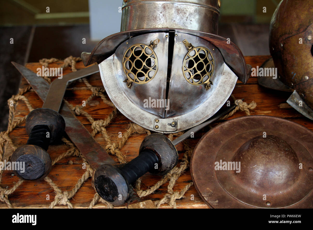 Roman gladiator Helm, wie von Gallus oder Murmillo Gladiatoren getragen, mit einer Auswahl von Schwertern angezeigt, und ein kleines Schild Stockfoto