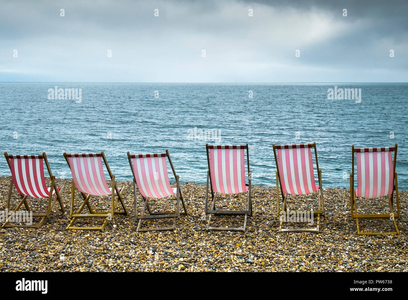 Eine Reihe von rot-weiß gestreiften Liegestühle auf Bier Strand in Devon. Stockfoto