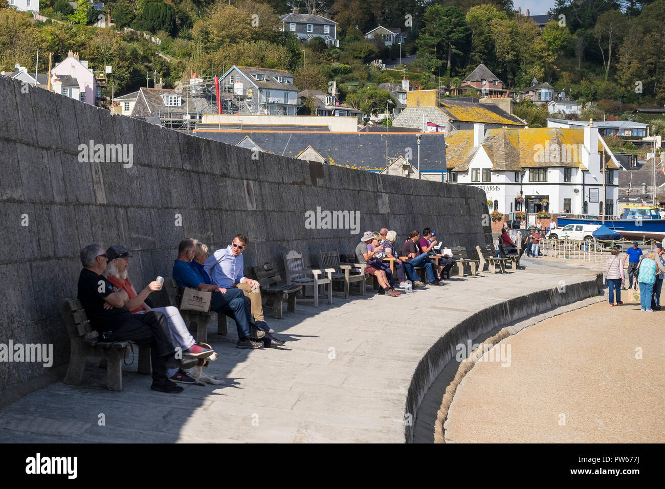 Menschen sitzen und entspannen auf dem Cobb in der Küstenstadt Lyme Regis in Dorset. Stockfoto