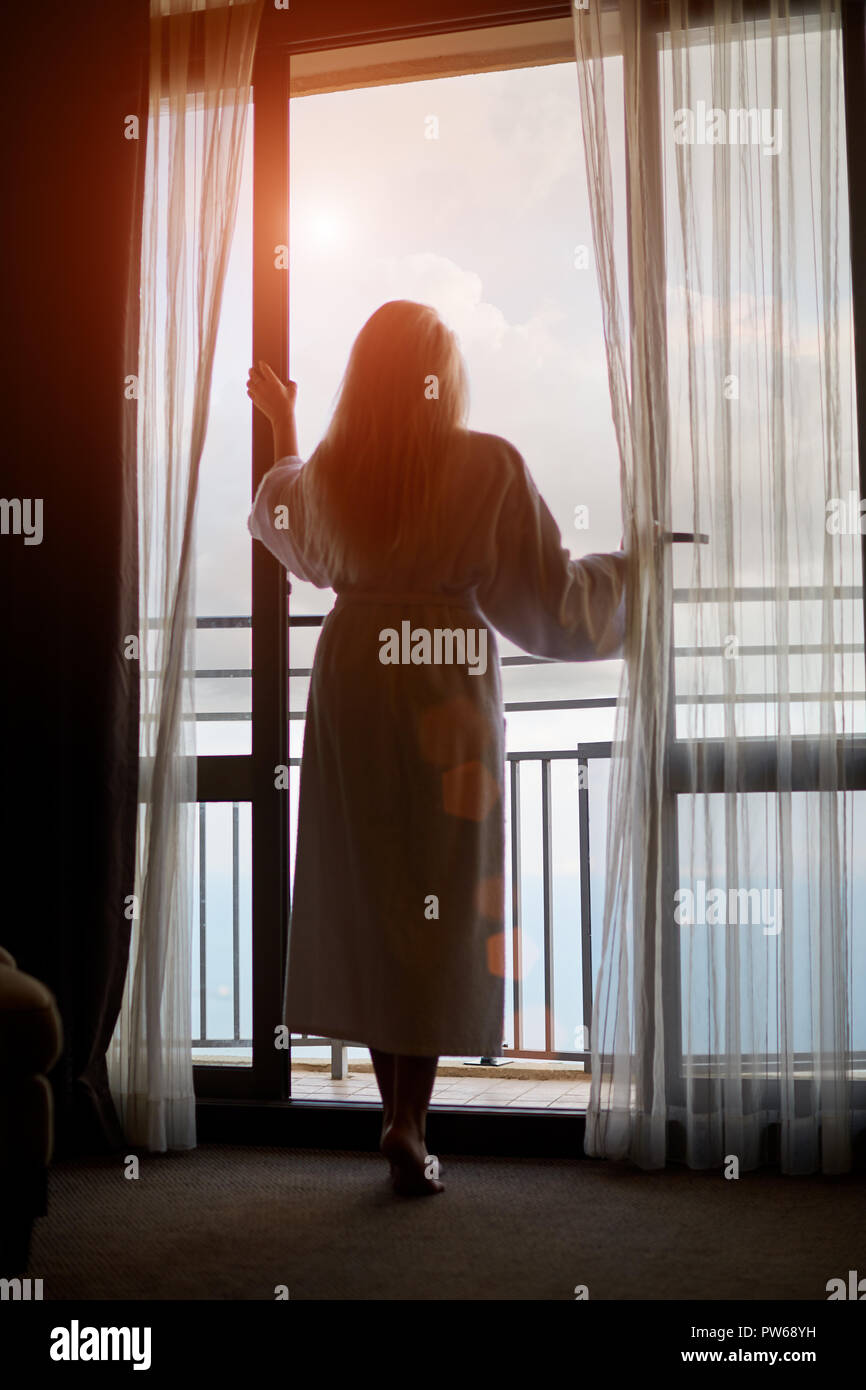 Silhouette der junge Frau schaut aus dem Fenster Stockfoto
