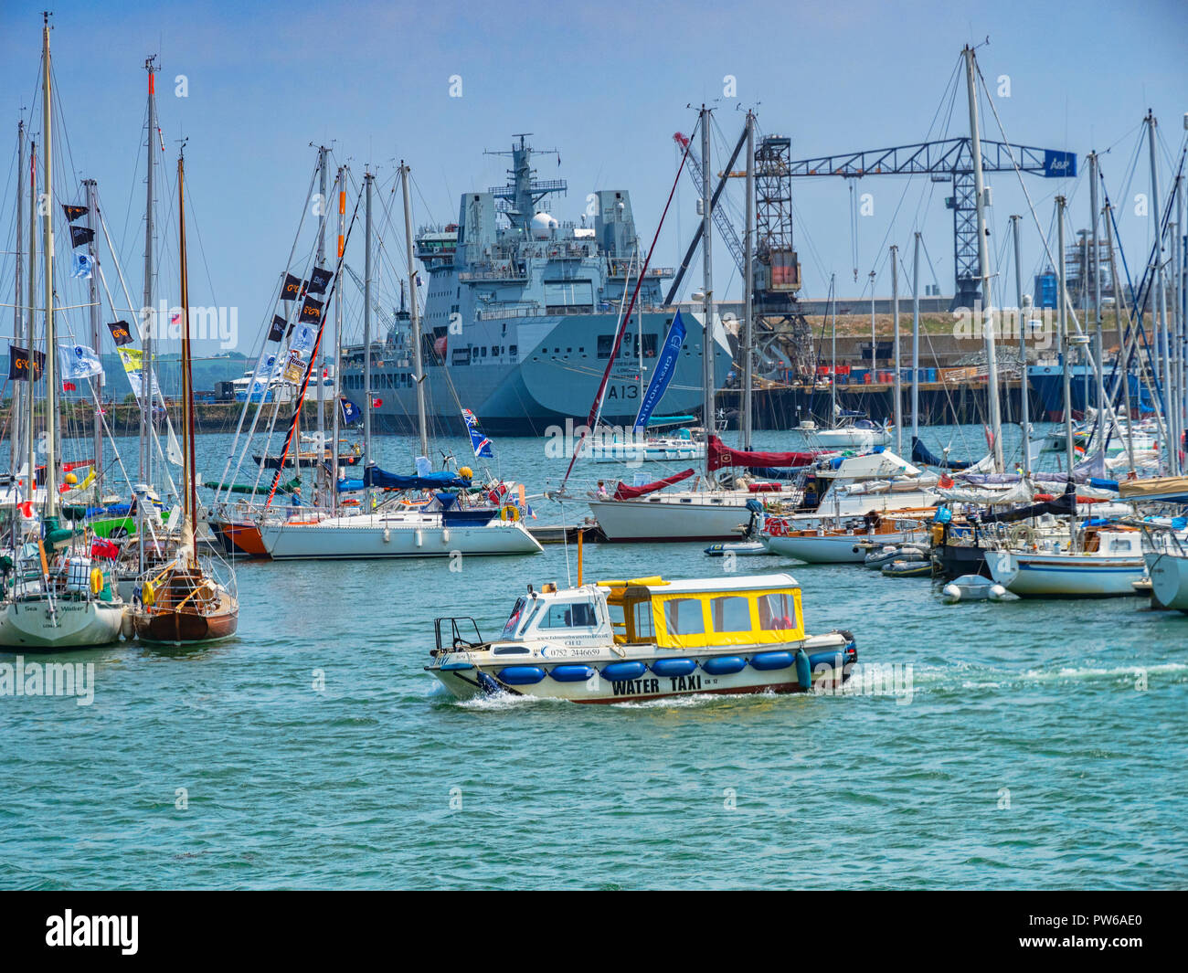 12. Juni 2018: Falmouth, Cornwall, UK-Wassertaxi überqueren Falmouth Harbour, mit einem Hintergrund von Booten und einem Kriegsschiff im Dock. Stockfoto