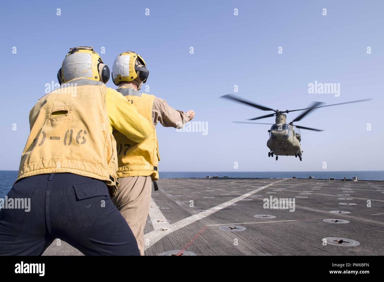 5. Flotte EINSATZGEBIET (Okt. 2010) 2, 2017) Marine Cpl. Ryan Carr (rechts), ein Eingeborener von Oceanside, Kalifornien, zu der Bekämpfung Cargo Abteilung zugewiesen an Bord der Amphibischen dock Landung Schiff USS Pearl Harbor (LSD 52), leitet ein CH-47D Chinook, zugeordnet zu den Armee Bravo Company, 2.BATAILLON, 149 Allgemeine Unterstützung Aviation Battalion (Gsab), wie es landet auf dem Schiff Flight Deck. Pearl Harbor ist Teil der Amerika Amphibious Ready Group (ARG) und, mit dem begonnen 15 Marine Expeditionary Unit (MEU), ist zur Unterstützung der Maritime Security Operations und Theater Sicherheit Zusammenarbeit bereitgestellt Stockfoto