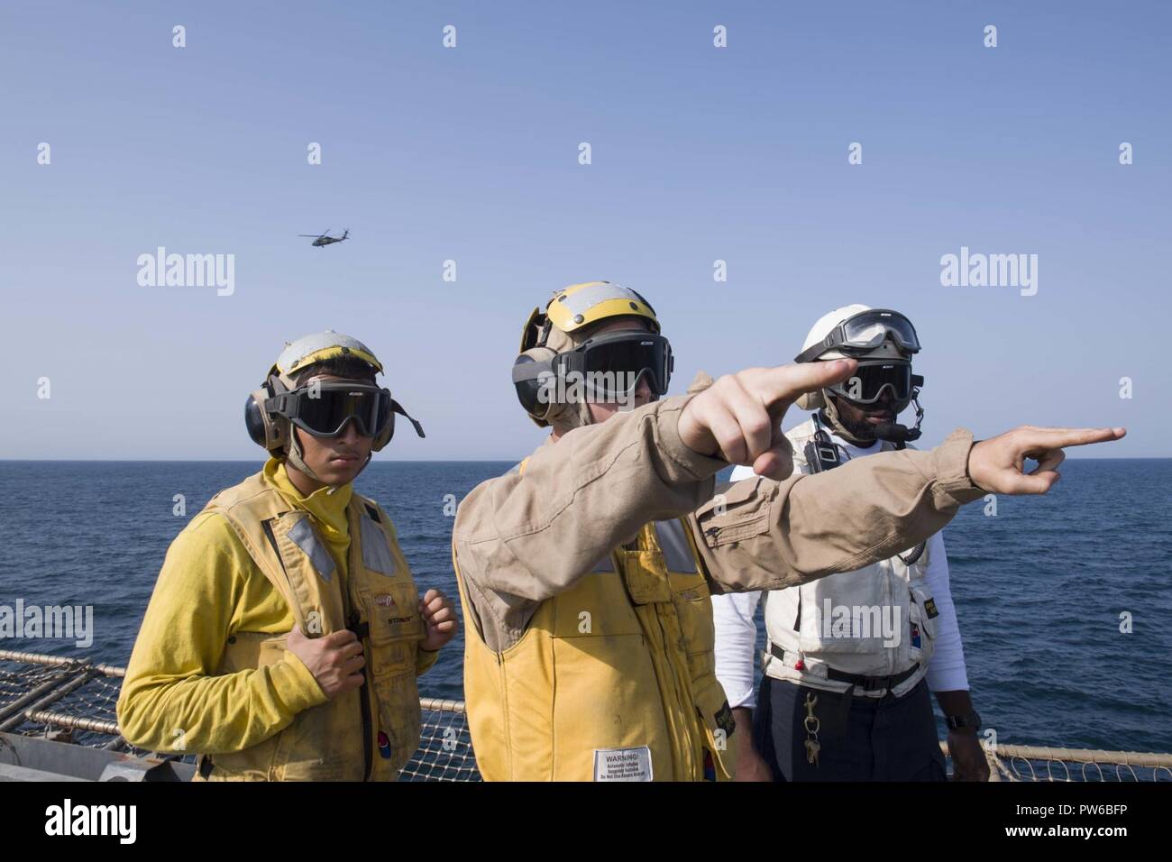 5. Flotte EINSATZGEBIET (Okt. 2010) 2, 2017)) Marine Cpl. Ryan Carr (Mitte), ein Eingeborener von Oceanside, Kalifornien, zu der Bekämpfung Cargo Abteilung zugewiesen an Bord der Amphibischen dock Landung Schiff USS Pearl Harbor (LSD 52), leitet den Flugbetrieb auf dem Schiff Flight Deck als Seemann Miguel Mendez (links) und der bootsmann Mate 1. Klasse Deshawn Byers (rechts), beide auf Deck des Schiffes Abteilung zugewiesen, beobachten. Pearl Harbor ist Teil der Amerika Amphibious Ready Group (ARG) und, mit dem begonnen 15 Marine Expeditionary Unit (MEU), ist zur Unterstützung der Maritime Security Operations und Thea bereitgestellt Stockfoto
