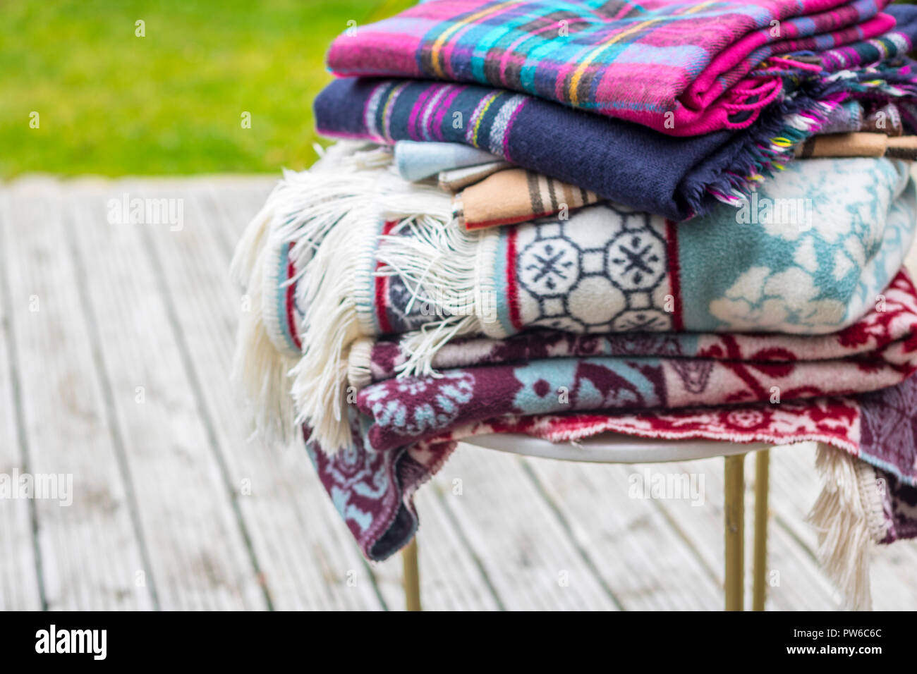 Stapel decken auf einem Tisch im Garten, im Sommer abends Konzept, warm Wärme, Creme fringe Picknick, Outdoor al fresco Konzept hygge Entspannen Entspannen Stockfoto