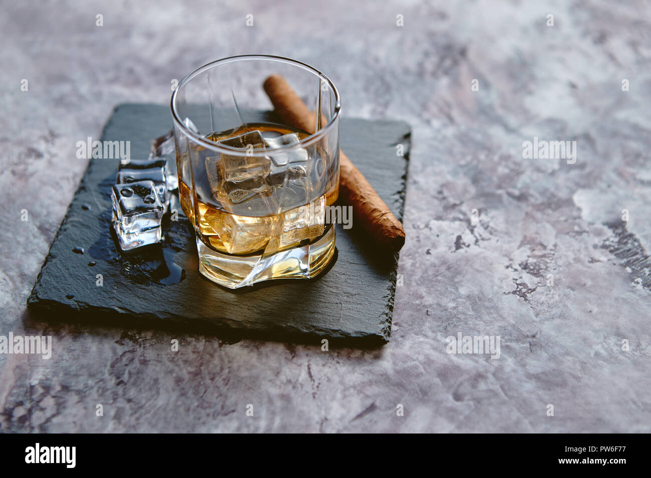 Glas Whisky mit Eiswürfel und Zigarre Stockfoto