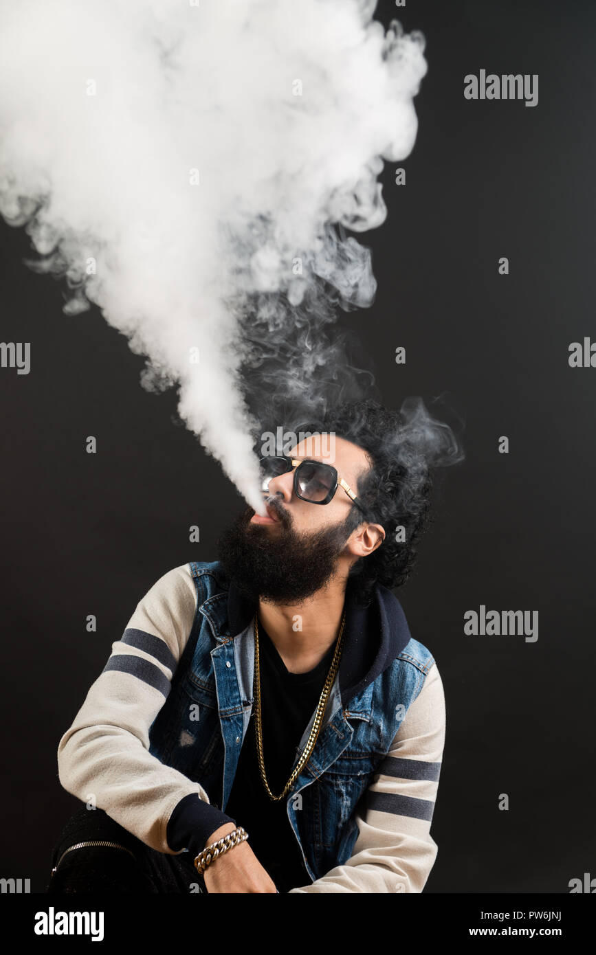 Junger Mann mit Bart vaping eine elektronische Zigarette nach oben. Vaper hipster Rauch Vaporizer. Schwarzer Hintergrund Stockfoto