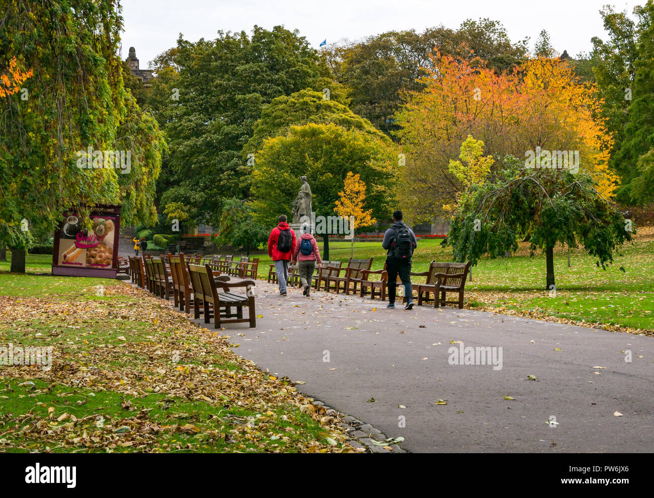 Menschen zu Fuß vorbei an Holzbänken im Princes Street Gardens mit Herbst Blatt Farben, Edinburgh, Schottland, Großbritannien Stockfoto