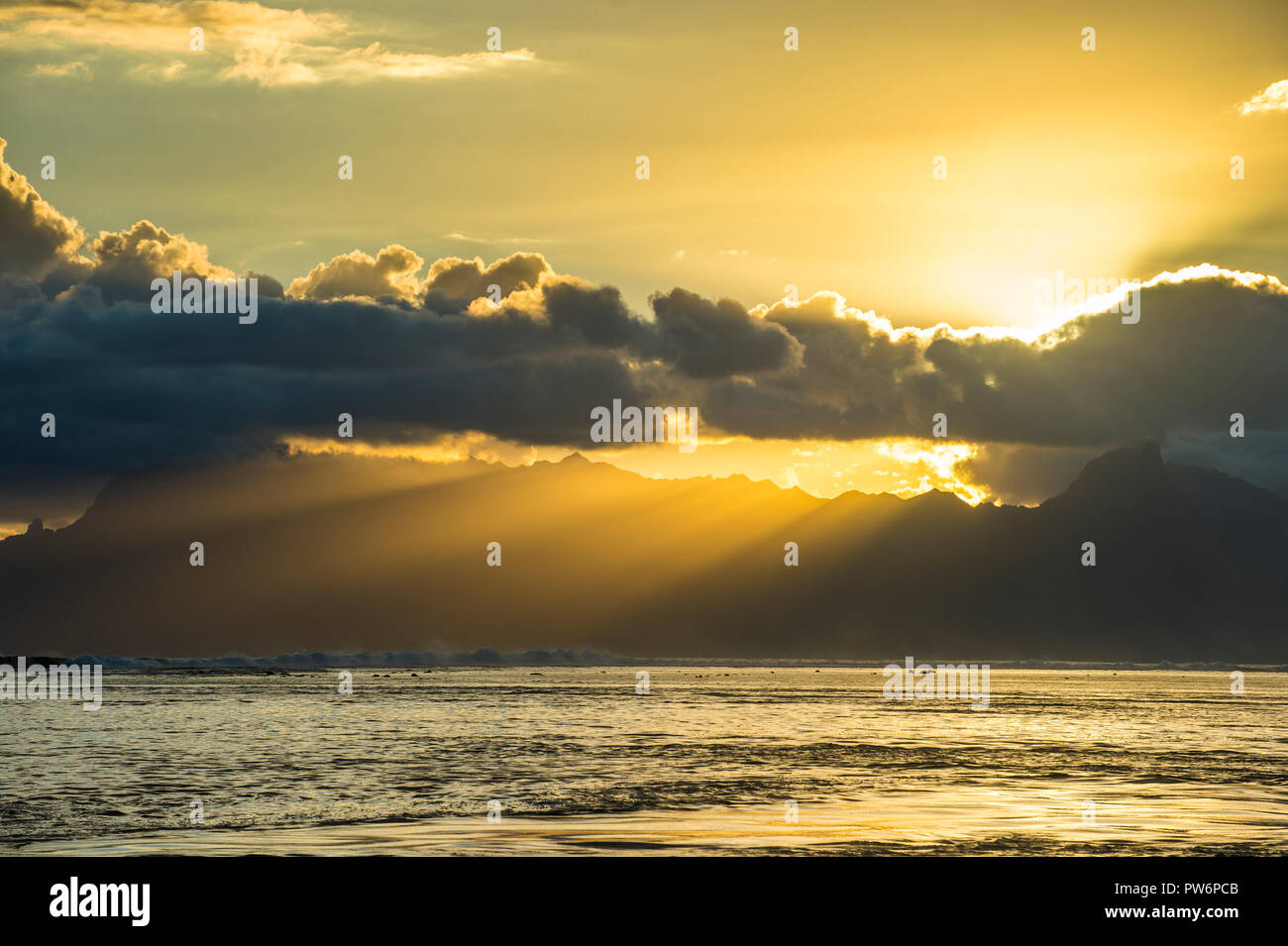 Sonnenstrahlen durch die Wolken über breakig Moorea, Papeete, Tahiti Stockfoto