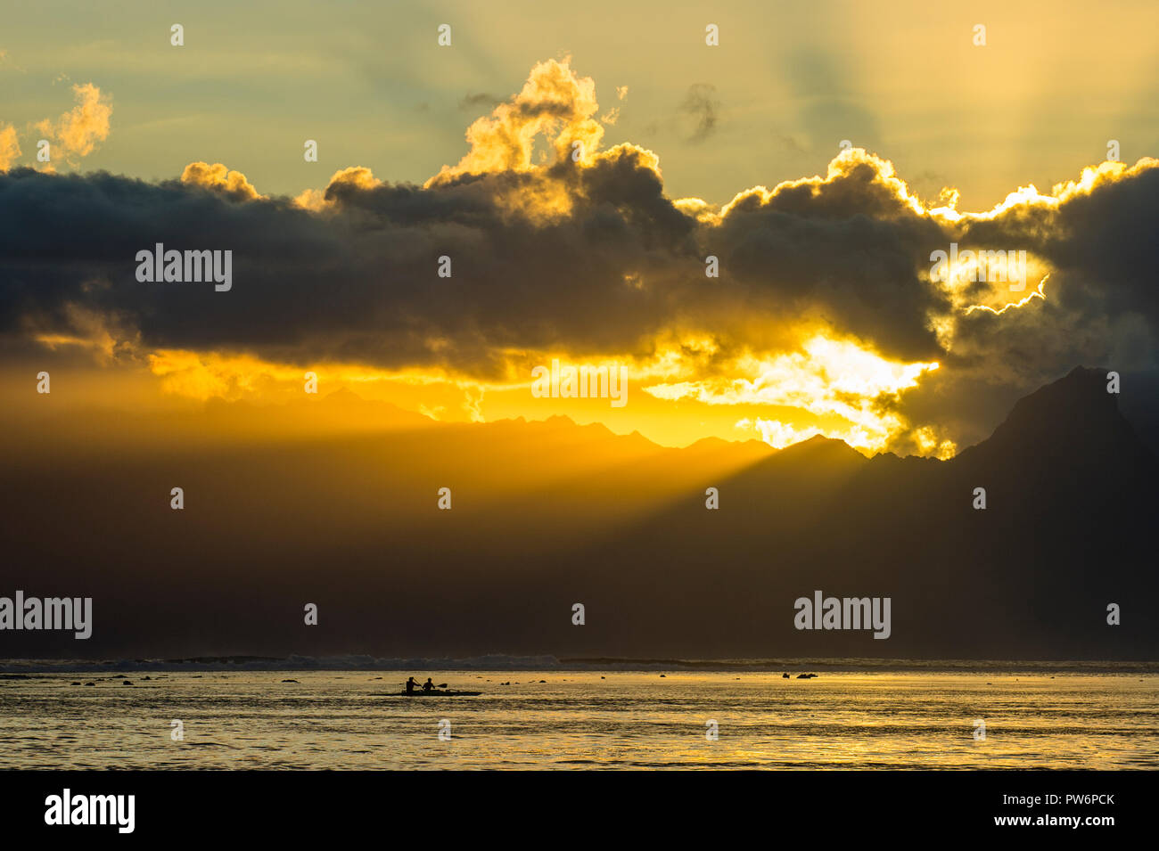 Silhouette von breakig kaykaers, Sonnenstrahlen durch die Wolken über Moorea, Papeete, Tahiti Stockfoto