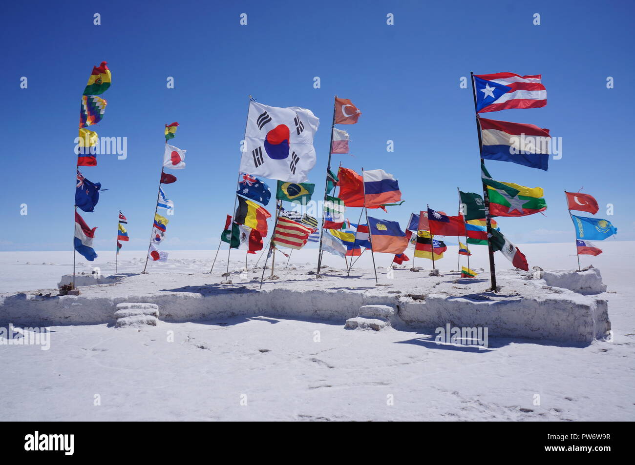 Eine Insel der Flags in der Mitte des Salar de Uyuni (bolivianischen Salt Flats), die eine Einheit von Nationen, Bolivien, Südamerika Stockfoto
