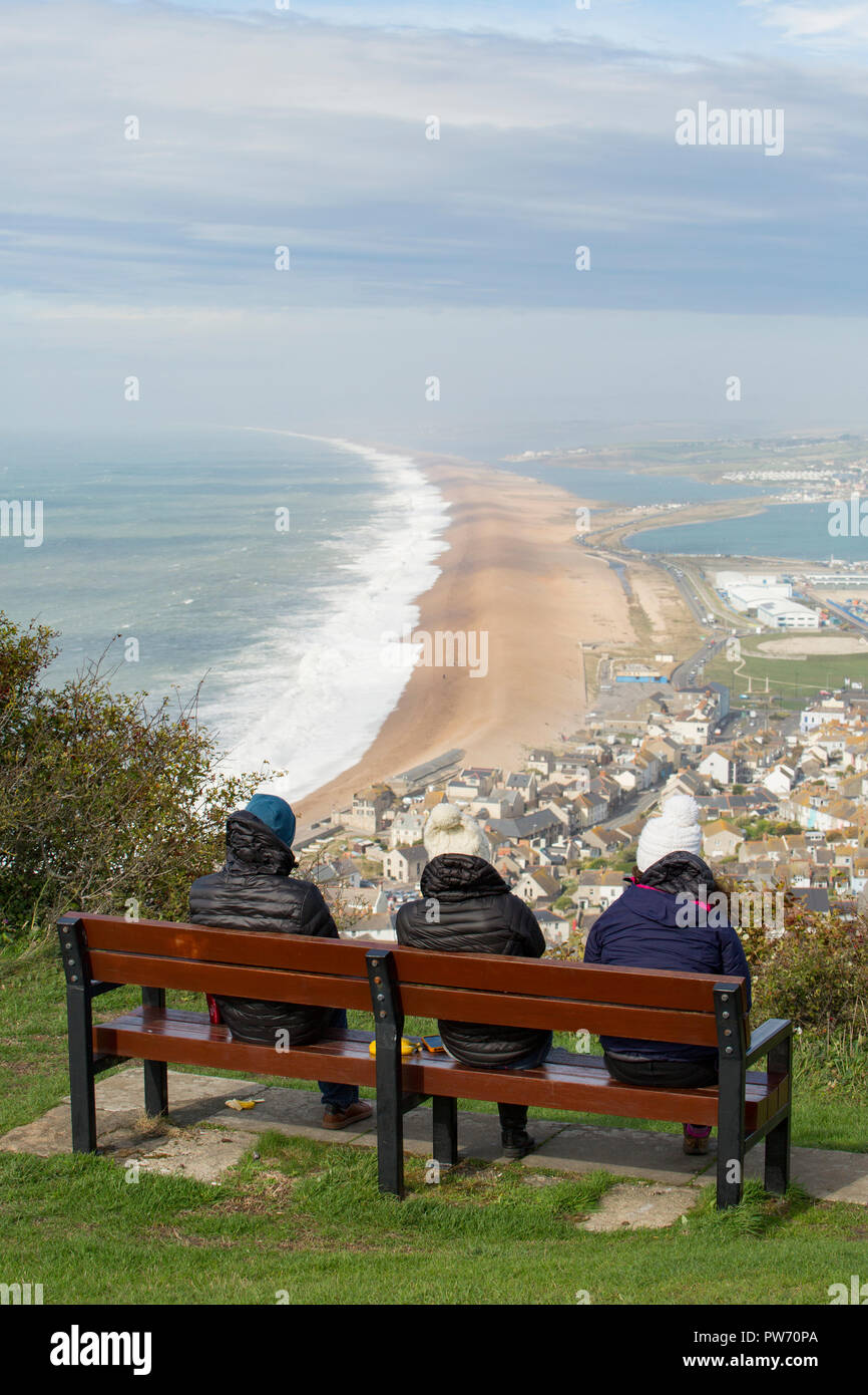 Drei Leute, die sich von der Isle of Portland als mächtige Wellen am Chesil Beach bei Unwetter Callum. Dorset England UK GB 13.10.2018 Stockfoto