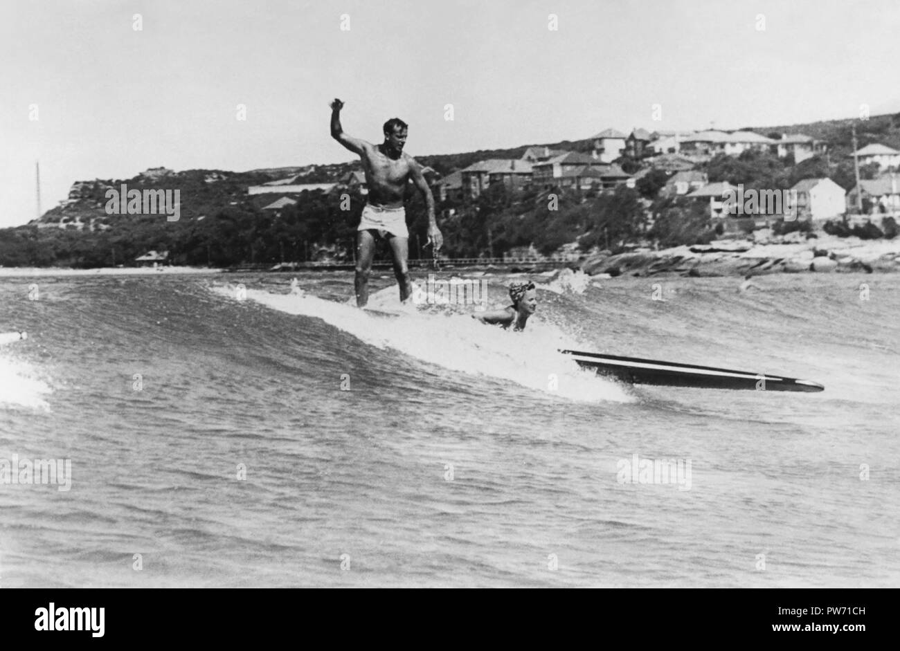 Mann und Frau auf einem longboard surfen Tandem 1945 an der Manly Beach, Sydney, Australien. (Foto von Ray Leighton) Stockfoto
