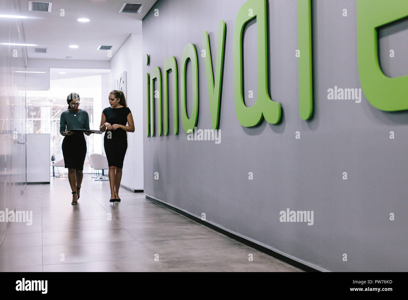 Die ganze Länge der beiden Business Frauen gehen durch Büro Flur. Weibliche Mitarbeiter im Büro Flur. Stockfoto