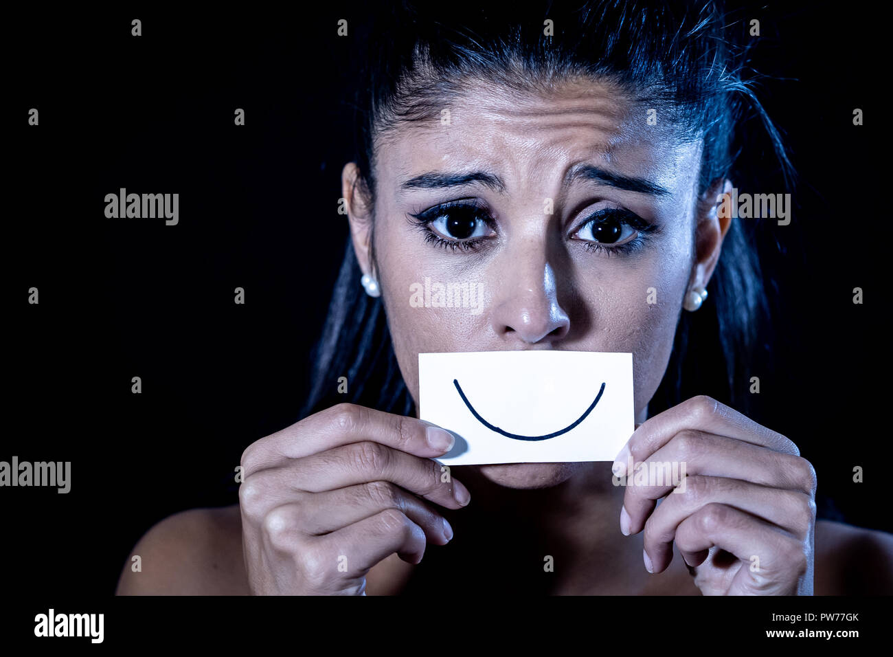 Dramatische Nahaufnahme Portrait von traurige Frau ihre Depression verstecken mit Lächeln auf Papier in der menschlichen Emotion leiden in der Stille depression Konzept iso lackiert Stockfoto