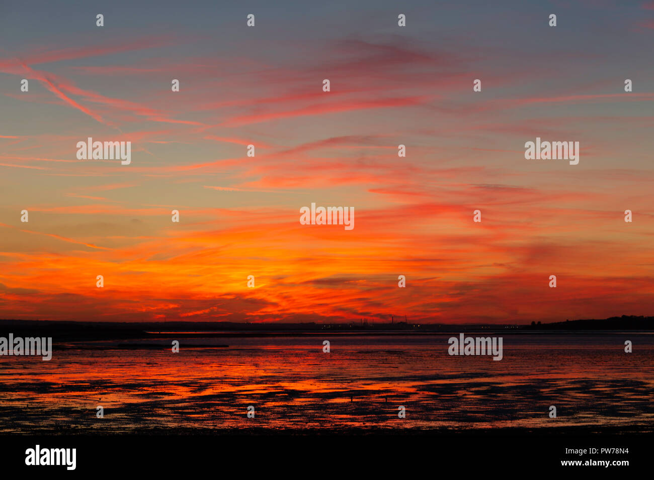 Flammend roten Sonnenuntergang und dramatische Wolken bei Seasalter Whitstable Kent UK in der Gezeiten- Schlamm des Swale Mündung auf der Insel Sheppey. Stockfoto