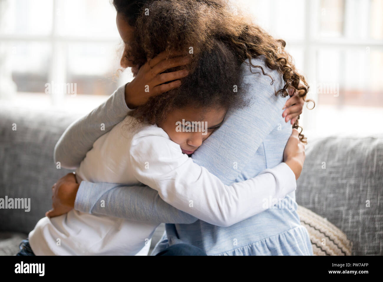 Schwarze Mutter und Tochter umarmen Sitzen auf der Couch Stockfoto