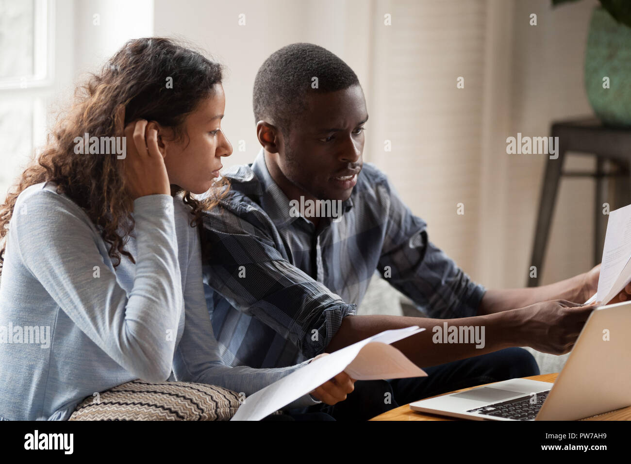Schwarz Paar mit Rechnungen und Laptop zu Hause betont Stockfoto