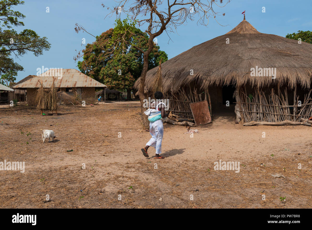 Orango Insel, Guinea-Bissau - Februar 3, 2018: eine Mutter sein kleines Kind tragen auf der Rückseite im Dorf Eticoga auf der Insel Orango. Stockfoto