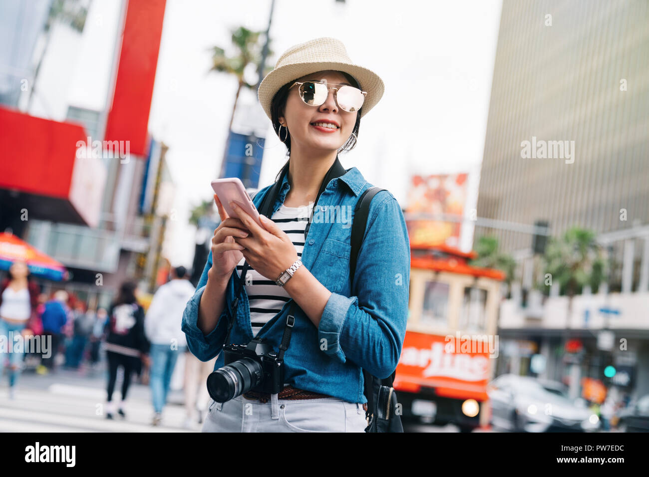 Attraktiven weiblichen Reisenden mit ihrem Telefon die Richtung zum nächsten Ort zu prüfen. Person in Jean jacket besuchen LA. Objektiv Frau reist in den USA Konzept. Stockfoto