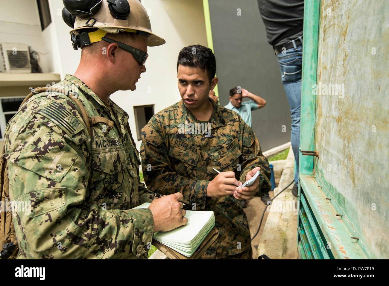 U.S. Navy Sailor Bau Elektriker 2. Klasse John McConnell, Links, mit Amphibischen Bau Bataillon 2, beschriftet die Deutsch-englisch Übersetzungen über einen defekten Generator von Hospitalman Lehrling Judd A. Ostolaza, ein Anwohner und reservist mit loslösung 1, Sitz & Service Unternehmen, 4. Marine Logistics Group, Freiwilligenarbeit, seine Übersetzung Dienstleistungen mit dem 26 Marine Expeditionary Unit (MEU), als Teil der Hurrikan Maria Hilfsmaßnahmen bei Ryder Krankenhaus, Humacao, Puerto Rico, Sept. 27, 2017. Die 26. MEU unterstützt die Federal Emergency Management Agency, der Leitung Stockfoto