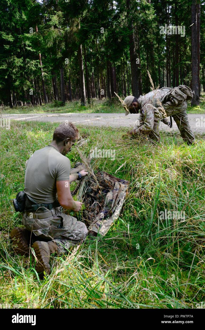 Ein US-Soldat, Links, auf die 173Rd Airborne Brigade zugeordnet, und ein Britischer Soldat bereiten ihre tarnanzügen durch Klagen beim Europäischen beste Sniper Squad Konkurrenz an der 7th Army Training Befehl Grafenwöhr Training Area, Germany, Sept. 27, 2017. Die Europäische beste Sniper Squad-Wettbewerb ist eine US-Armee Europa Konkurrenz, anspruchsvolle Militärs aus ganz Europa zu konkurrieren und die Zusammenarbeit mit Verbündeten und Partner Nationen verbessern. Stockfoto