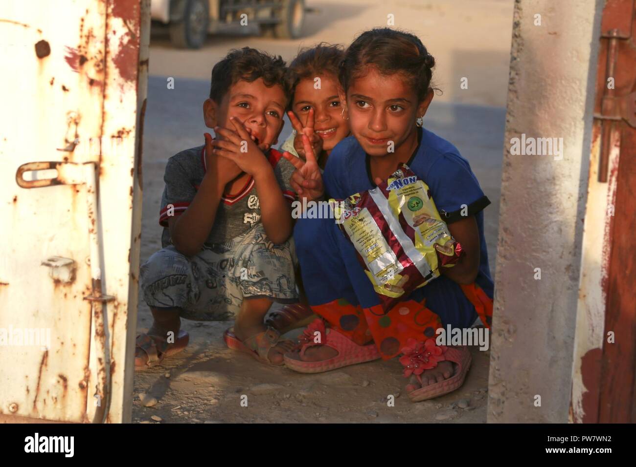 Drei Kinder mit Koalition Mitglieder kommunizieren, während ein Gate eines intern Vertriebenen screening Point der Hajj Ali, Irak, 27. September 2017. Stockfoto