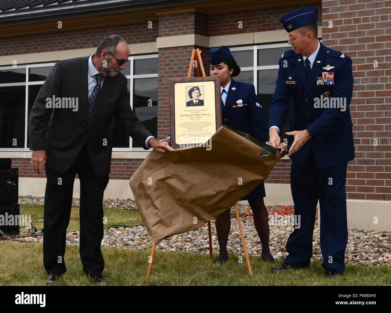 Wald R. McDonald, Sohn von Ola "Millie" Rexroat und Oberst John Edwards, der Kommandant der 28. Bombe Flügel, die Plakette ehren Rexroat während eines Gebäudes Hingabe an Ellsworth Air Force Base, Okt. 2, 2017 vorstellen. Beim Dienen als eine Wespe, Rexroat Ziele hinter einem T-6 Texan abgeschleppt für Luft-zu-Luft schießwesen und-anti-aircraft Praxis für männliche Piloten. Sie transportiert auch Personal und Fracht. Nachdem die Wespen aufgelöst, Rexroat serviert weitere zehn Jahre in der Luftwaffe behält sich als Fluglotse. Stockfoto