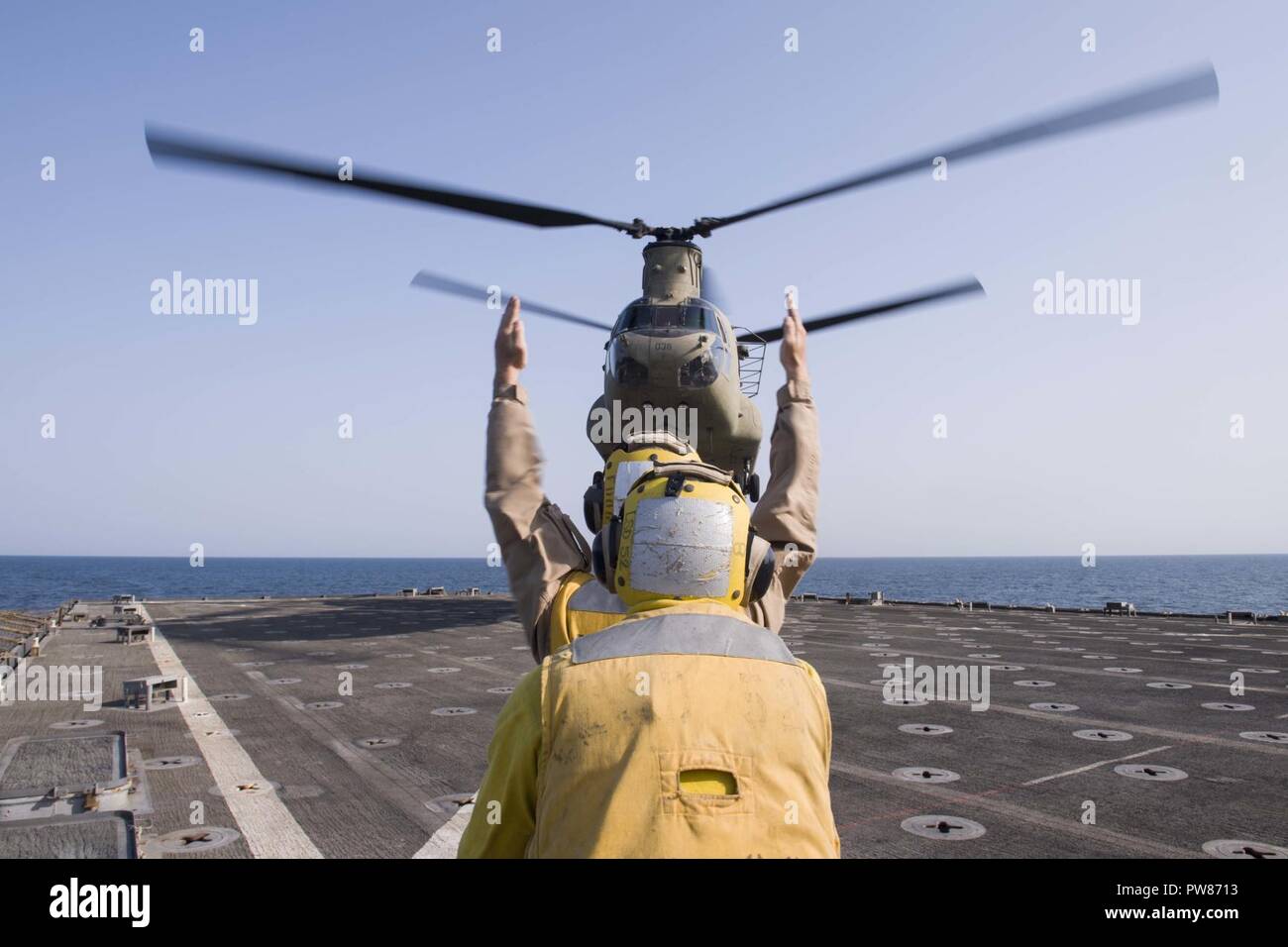 5. Flotte EINSATZGEBIET (Okt. 2010) 2, 2017) Marine Cpl. Ryan Carr, ein Eingeborener von Oceanside, Kalifornien, zu der Bekämpfung Cargo Abteilung an Bord der Amphibischen dock Landung Schiff USS Pearl Harbor (LSD 52), unterstützt von Seaman Miguel Mendez (vorne), ein Eingeborener von Orlando zugewiesen ist, leitet ein CH-47D Chinook, zugeordnet zu den Armee Bravo Company, 2.BATAILLON, 149 Allgemeine Unterstützung Aviation Battalion (Gsab), wie es landet auf dem Schiff Flight Deck. Pearl Harbor ist Teil der Amerika Amphibious Ready Group (ARG) und, mit dem begonnen 15 Marine Expeditionary Unit (MEU), ist zur Unterstützung der maritimen Secu bereitgestellt Stockfoto