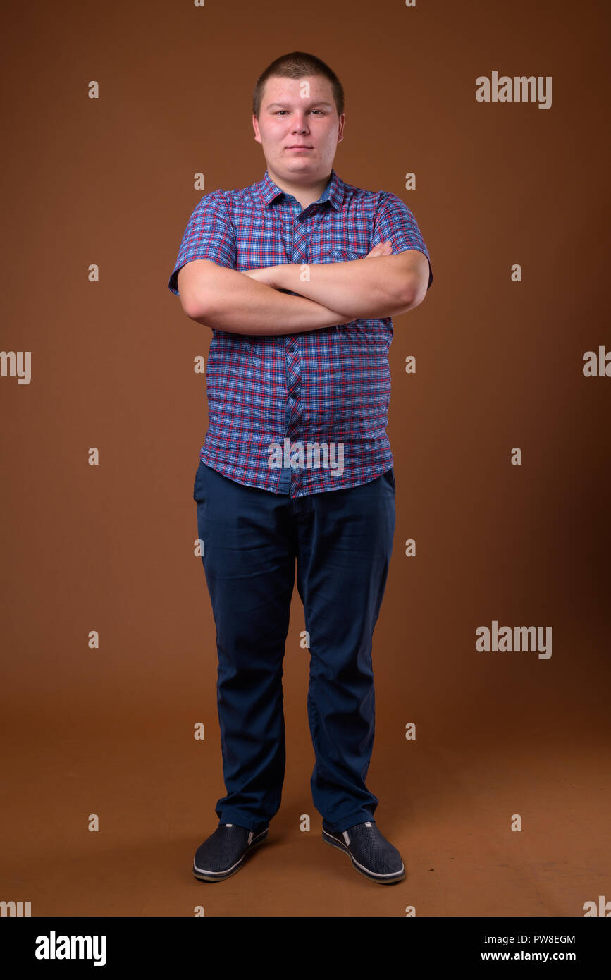 Studio für übergewichtige junge Menschen gegen den braunen Hintergrund Stockfoto