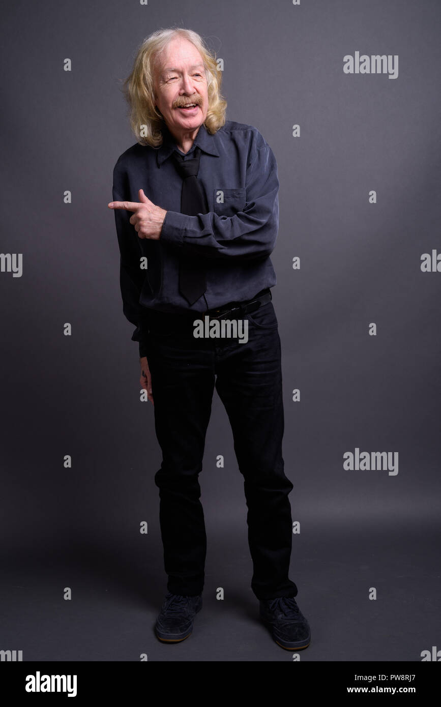 Senior Geschäftsmann mit Schnurrbart gegen grauer Hintergrund Stockfoto