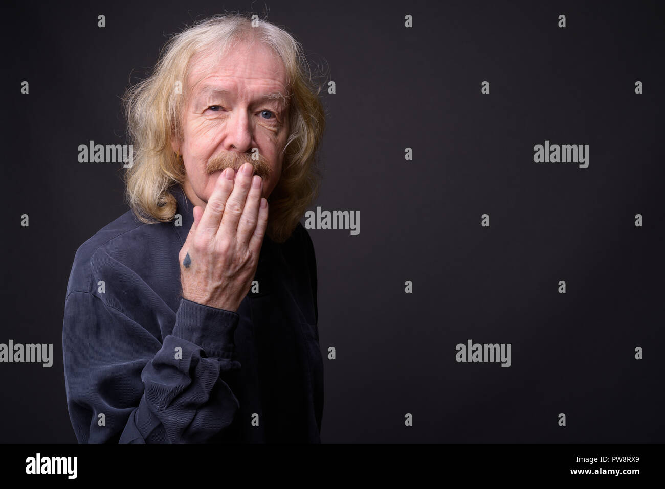 Senior Geschäftsmann mit Schnurrbart gegen grauer Hintergrund Stockfoto