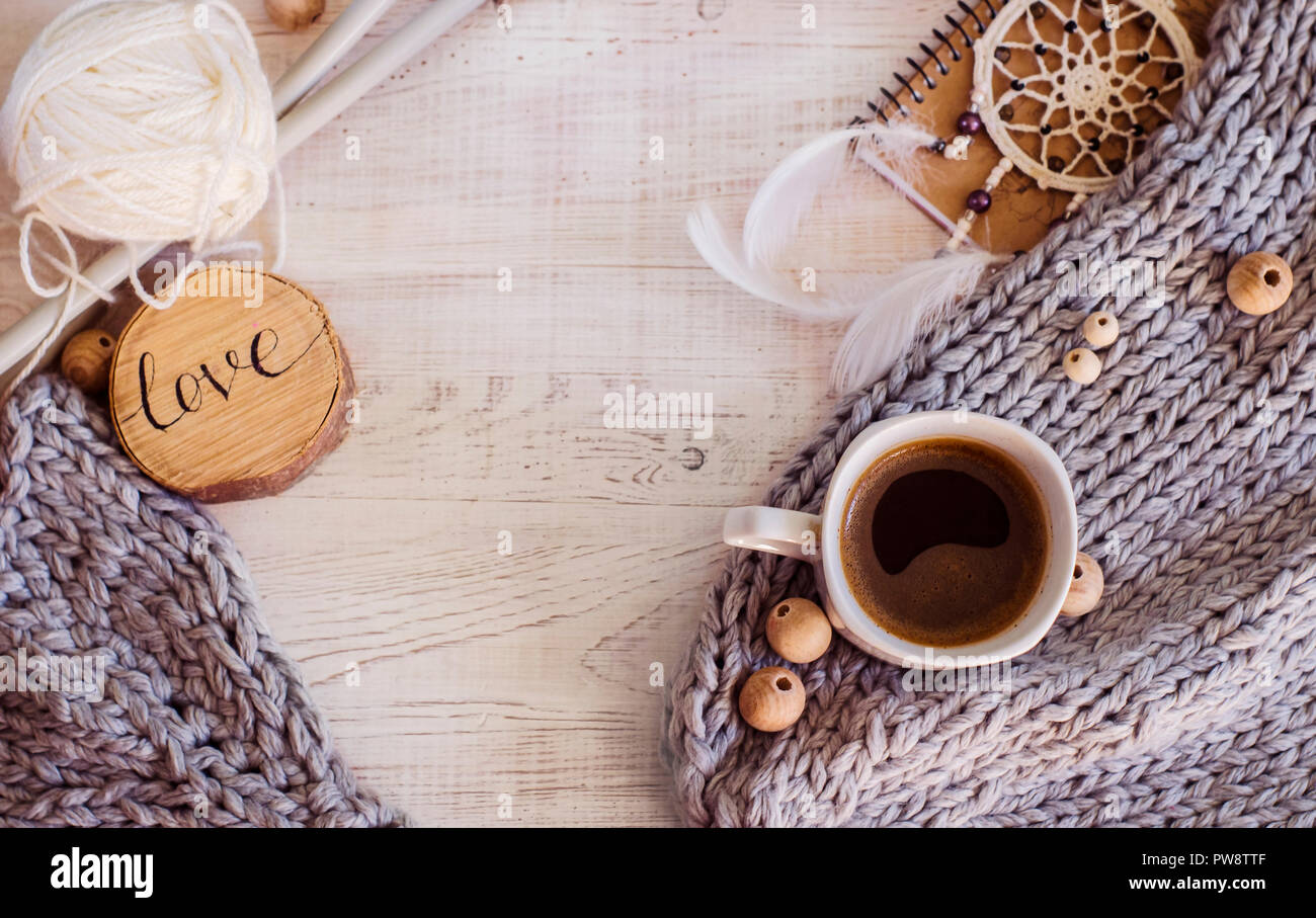 Gemütliche Zusammensetzung mit Kaffee, aus Gewirken Elemente aus Merinowolle auf einer hölzernen Hintergrund. Ein Foto in einem hygge Stil. Stockfoto
