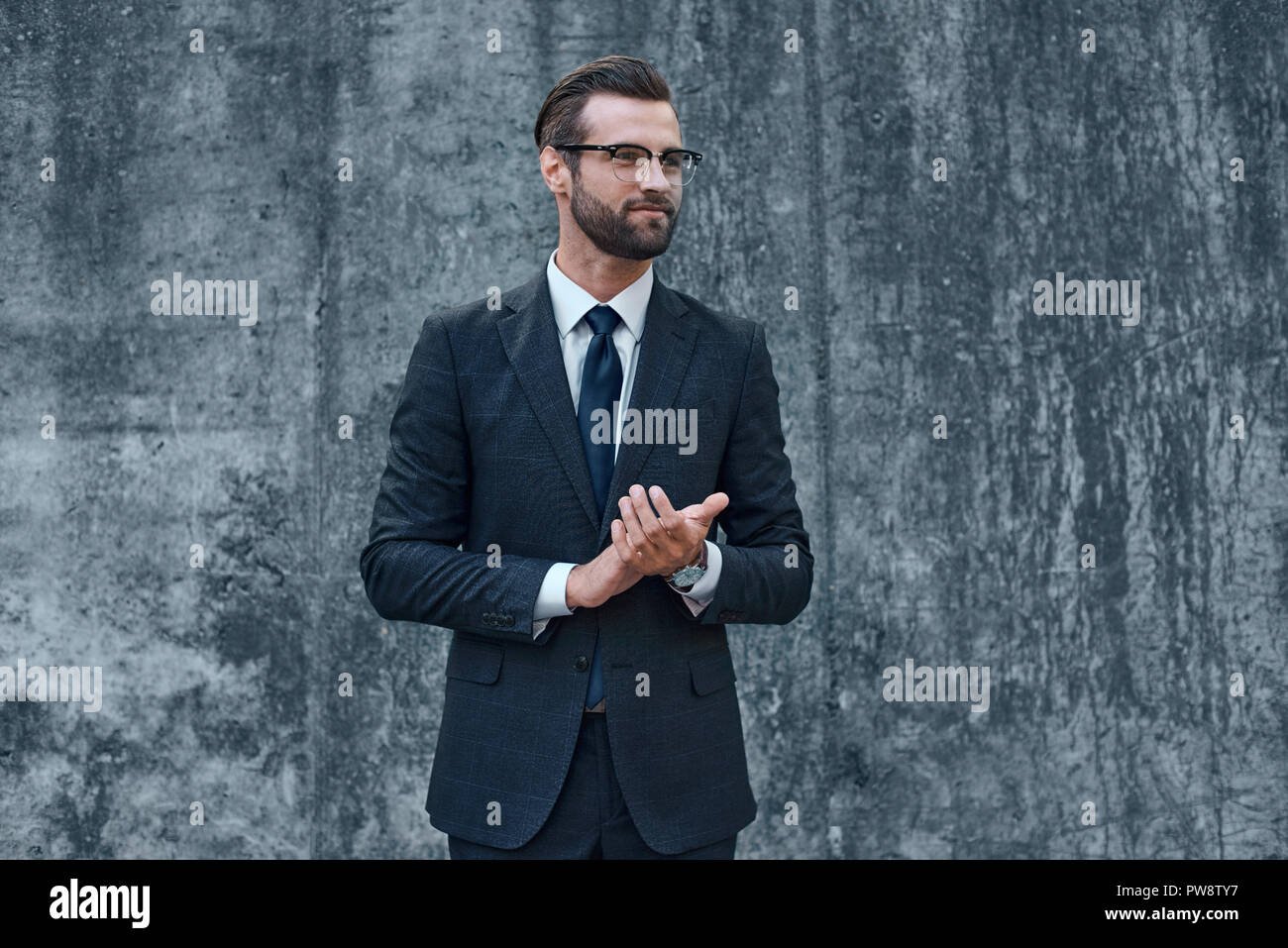 Ein junger Geschäftsmann mit Brille und Bart klatscht in die Hände Stockfoto
