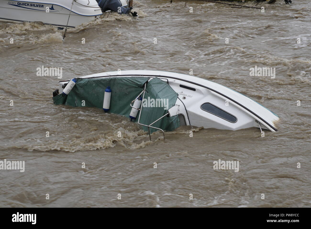 Aberaeron, UK. 13. Oktober 2018. Ein Bild der Verwüstung in Aberaeron Hafen auf der West Wales Küste am Nachmittag als schwerer Regen und starkem Wind vom Sturm Callum weiterhin Chaos zu verursachen. Flut, Wasser aus dem Fluss Aeron mit Bäumen und grossen Niederlassungen Crash in Boote es Schäden an vielen und völlig versinken. Credit: Anthony Pugh/Alamy leben Nachrichten Stockfoto