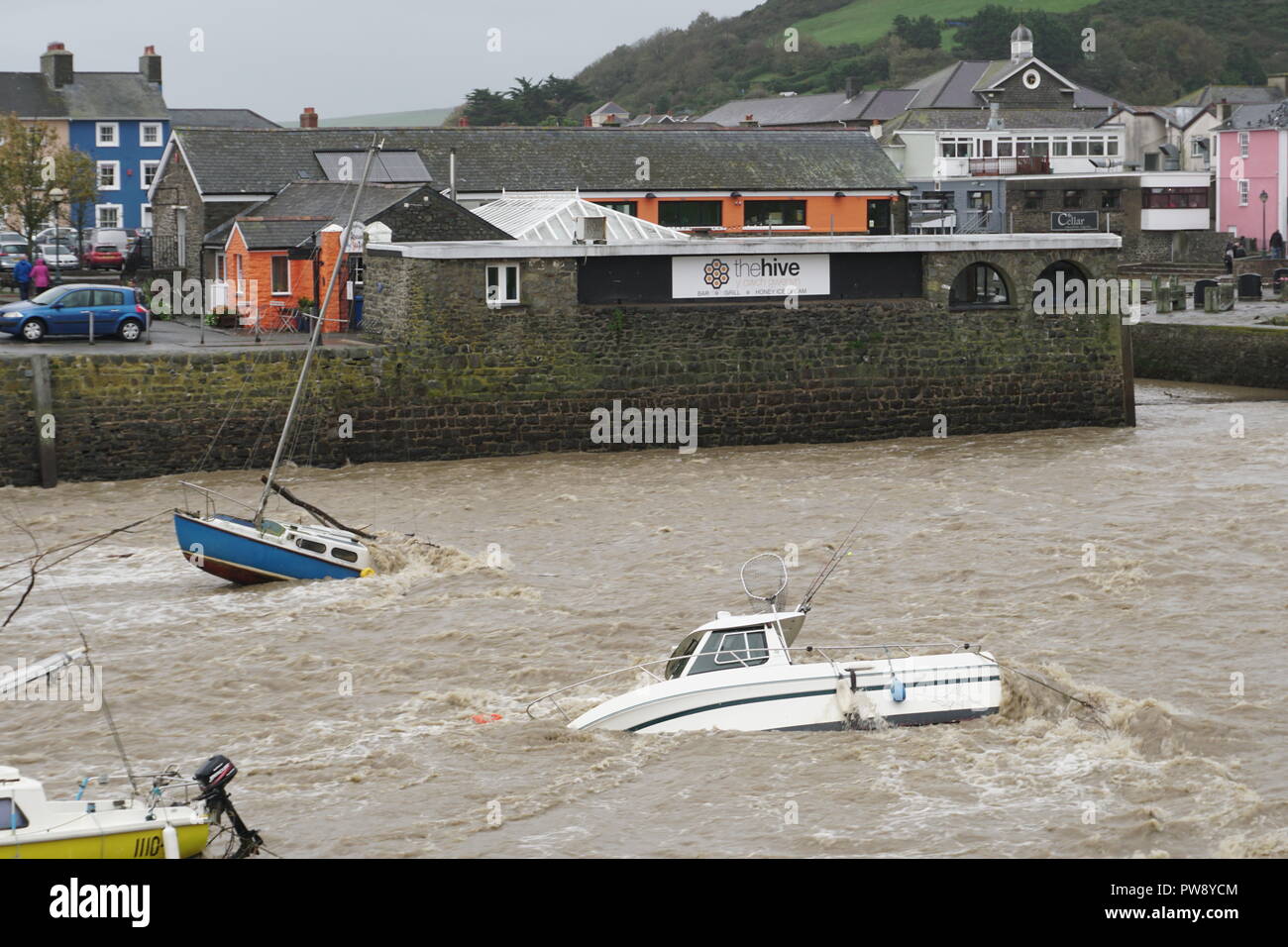 Aberaeron, UK. 13. Oktober 2018. Ein Bild der Verwüstung in Aberaeron Hafen auf der West Wales Küste am Nachmittag als schwerer Regen und starkem Wind vom Sturm Callum weiterhin Chaos zu verursachen. Flut, Wasser aus dem Fluss Aeron mit Bäumen und grossen Niederlassungen Crash in Boote es Schäden an vielen und völlig versinken. Credit: Anthony Pugh/Alamy leben Nachrichten Stockfoto